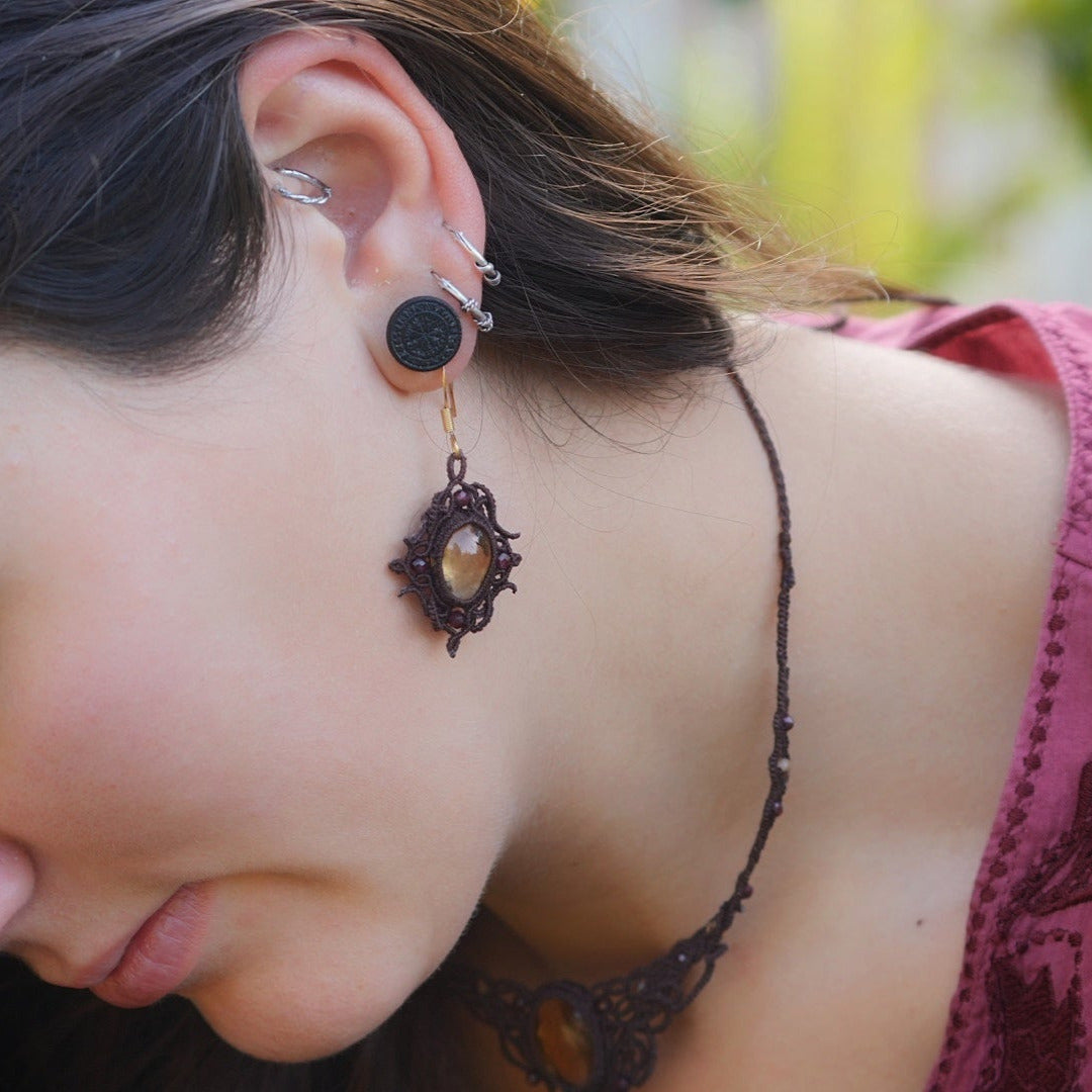 « Boucles d’oreilles elfiques losange en citrine dorée et grenat rouge, portées sur modèle à peau claire et cheveux bruns – Bijoux bohèmes artisanaux en micro macramé fait main en France »
