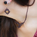 Collier ras de cou elfique en micro macramé brun, orné de citrine jaune dorée et de grenat rouge rosé. Bijou bohème réglable, porté par une femme à la peau claire et cheveux bruns, assorti à un vêtement rose profond.