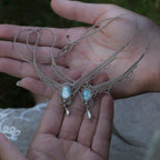 Duo de Bracelets de cheville bohème, ambiance plage et été sur les îles. Bijoux de pieds assortis. Micro macramé en fil de coton couleur lin beige avec une pierre de larimar bleu ciel accompagné d'une perle goutte argenté. Système de réglage à coulisse à l'arrière. Bijoux posé sur 2 mains dans un univers féérique bohème dans un jardin. Modèle avec Dreadlocks brunes, peau caramel et habits assorti au bijou de couleur lin naturel beige gris