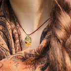Collier elfique réglable en micro macramé avec citrine ovale jaune pâle et fleur orange dorée. Bijou floral et lumineux de la collection Clairière de Miel, porté par une femme à la peau claire et cheveux bruns.